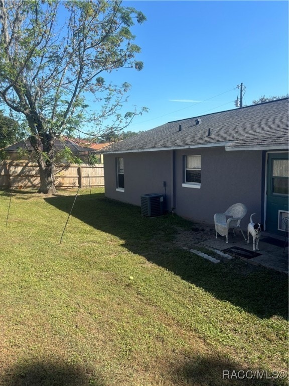 rear view of property featuring a yard and central AC