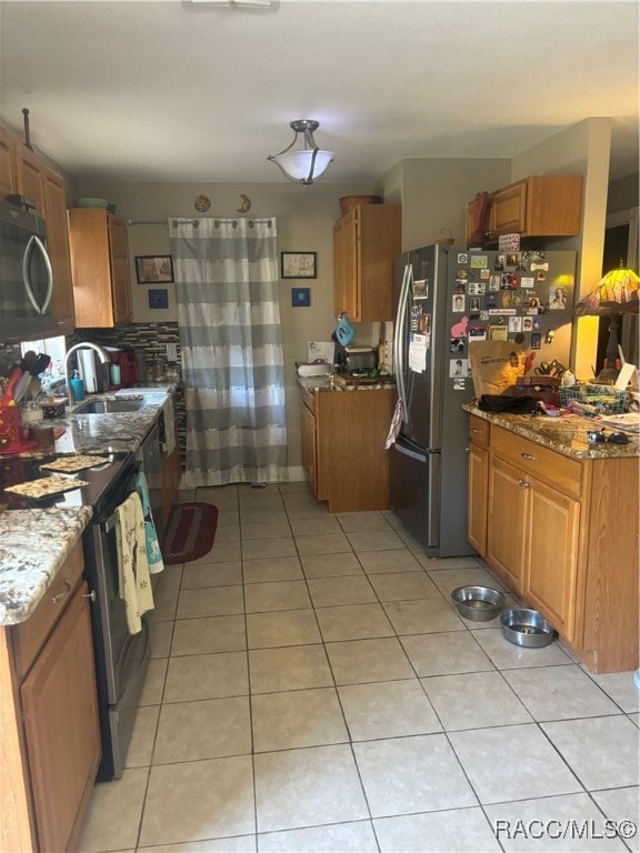 kitchen featuring light stone countertops, sink, light tile patterned floors, and appliances with stainless steel finishes