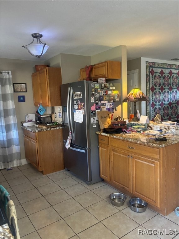 kitchen featuring stainless steel fridge with ice dispenser, light stone countertops, and light tile patterned floors