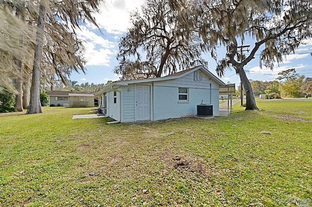 rear view of house featuring cooling unit and a lawn