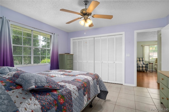 bedroom with ceiling fan, light tile patterned flooring, a textured ceiling, and multiple windows