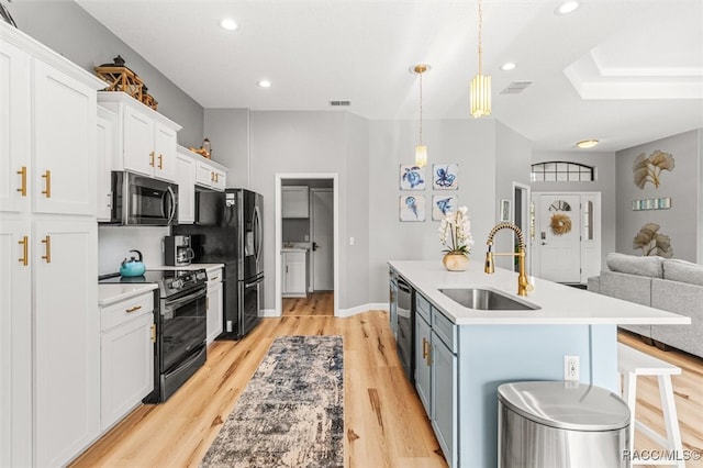 kitchen featuring black appliances, a kitchen breakfast bar, sink, light hardwood / wood-style floors, and white cabinetry