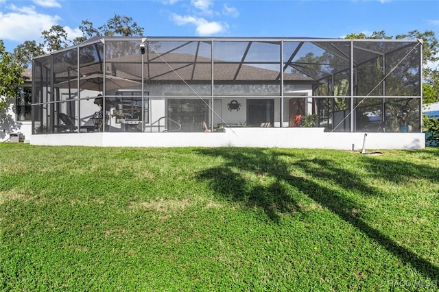 rear view of property with glass enclosure and a lawn