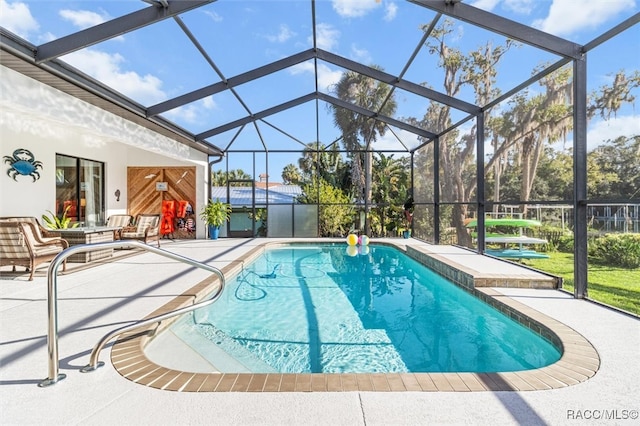 view of pool with glass enclosure and a patio