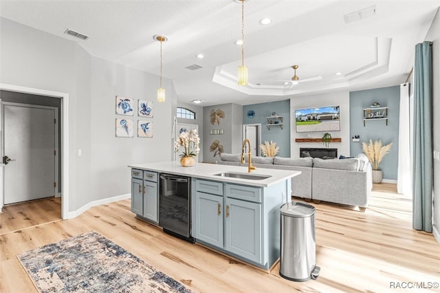 kitchen featuring a center island with sink, sink, light hardwood / wood-style flooring, ceiling fan, and decorative light fixtures