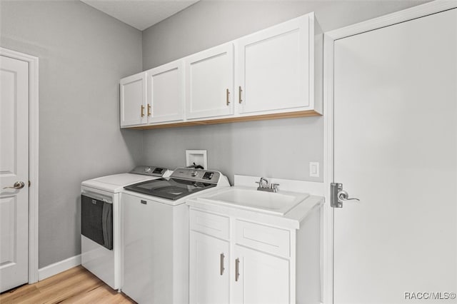 washroom with cabinets, sink, light hardwood / wood-style flooring, and washing machine and clothes dryer