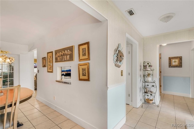 corridor with light tile patterned floors and crown molding