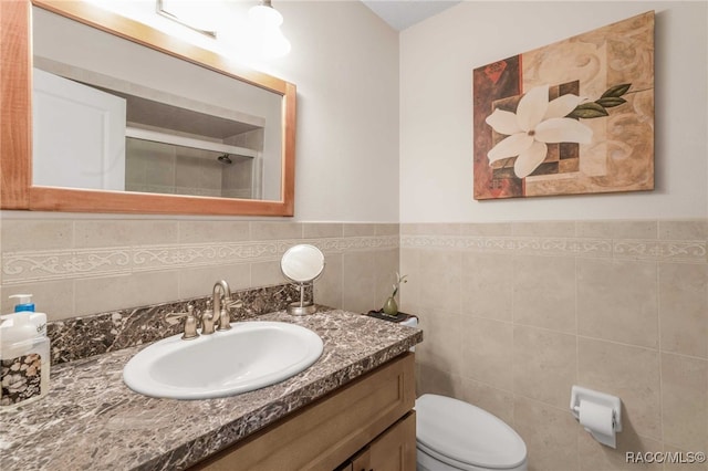 bathroom with toilet, tile walls, and vanity