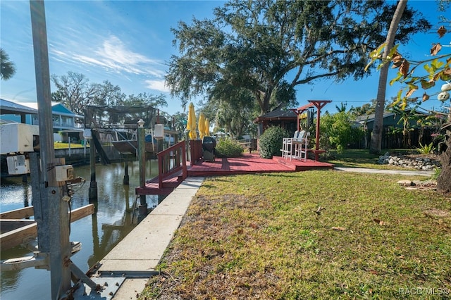 view of dock featuring a deck with water view and a yard