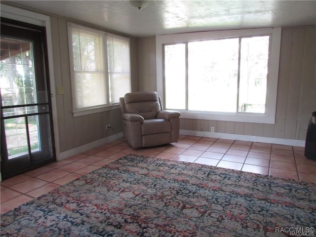 sitting room with wood walls, baseboards, and tile patterned floors