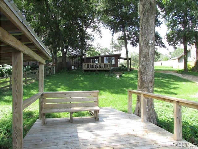 wooden terrace with a lawn and fence