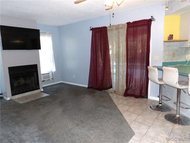 unfurnished living room with a wall mounted air conditioner, ceiling fan, and light tile patterned floors