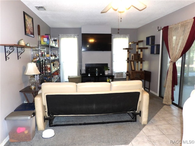 tiled living room featuring ceiling fan and a textured ceiling