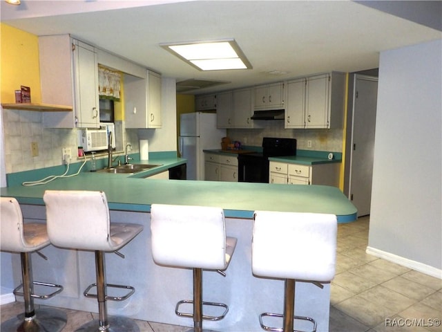 kitchen with a breakfast bar, kitchen peninsula, black range with electric cooktop, and white fridge