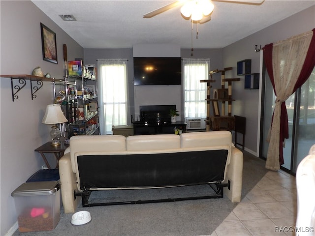 tiled living room featuring ceiling fan, cooling unit, and a textured ceiling