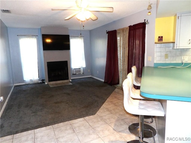 interior space featuring a wall mounted air conditioner, tasteful backsplash, white cabinetry, ceiling fan, and light carpet