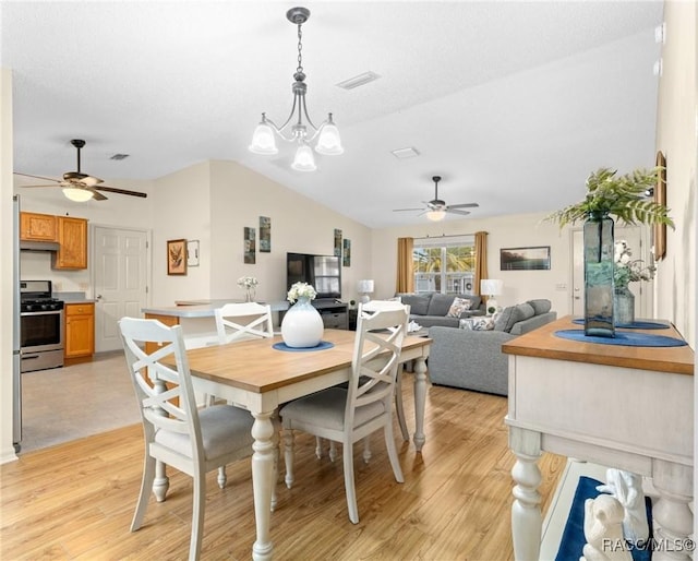 dining space featuring lofted ceiling, ceiling fan with notable chandelier, light hardwood / wood-style flooring, and a textured ceiling