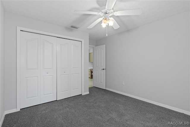 unfurnished bedroom with ceiling fan, a closet, and dark colored carpet