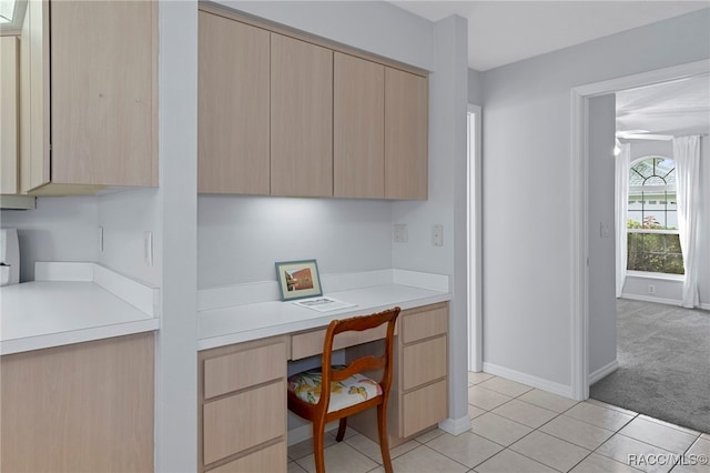 kitchen featuring light brown cabinetry, built in desk, and light tile patterned floors