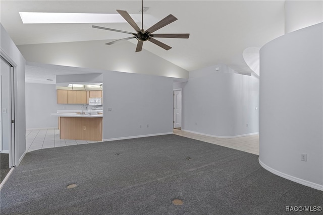 unfurnished living room with ceiling fan, light carpet, high vaulted ceiling, and a skylight