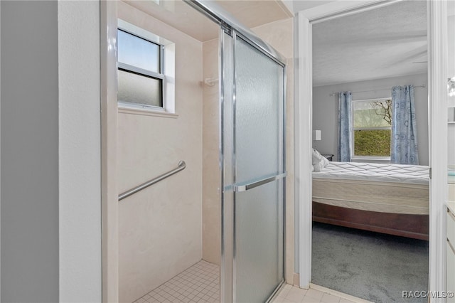 bathroom featuring tile patterned floors, plenty of natural light, a shower with door, and a textured ceiling