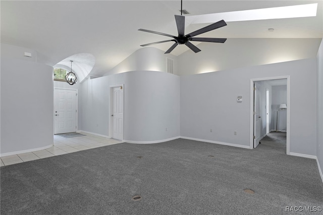 unfurnished living room with high vaulted ceiling, light colored carpet, and ceiling fan with notable chandelier