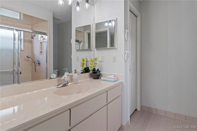 bathroom featuring tile patterned flooring, vanity, a shower with shower door, and toilet