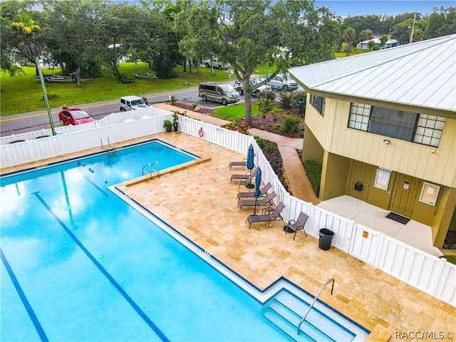 community pool with a fenced backyard, a lawn, and a patio area