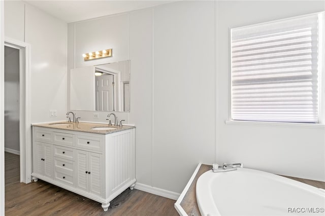7187 Montier St, Weeki Wachee, FL 34613 - full bathroom featuring double vanity, a bath, wood finished floors, and baseboards