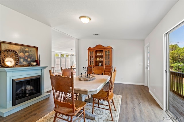 7187 Montier St, Weeki Wachee, FL 34613 - dining space with wood finished floors, baseboards, a fireplace with raised hearth, and a chandelier
