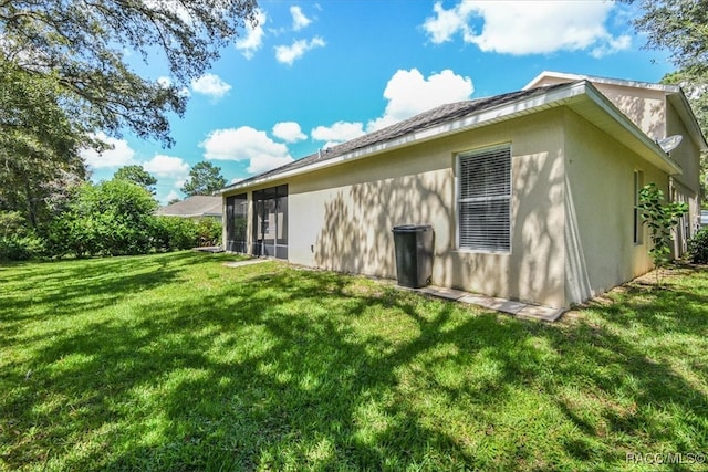 view of side of home with a sunroom and a yard