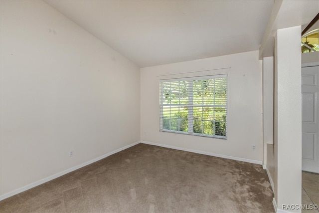 unfurnished room featuring light carpet and vaulted ceiling