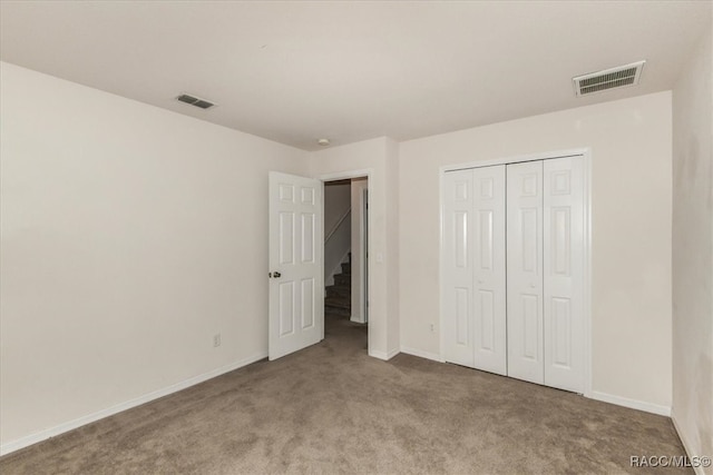 unfurnished bedroom with light carpet and a closet