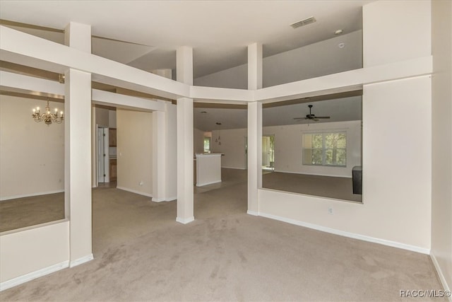 unfurnished living room featuring carpet flooring, ceiling fan with notable chandelier, and high vaulted ceiling