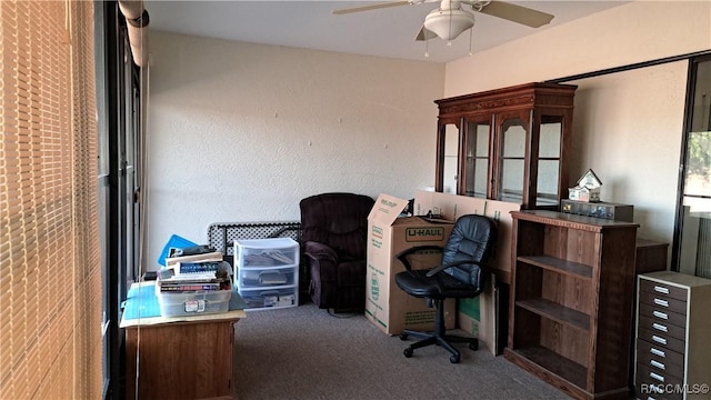 carpeted home office featuring ceiling fan