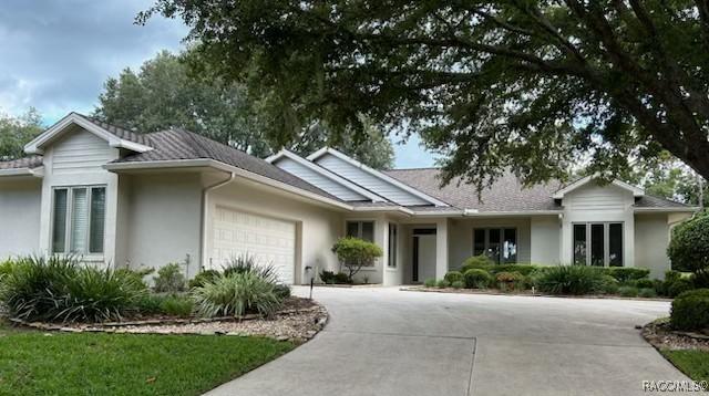 ranch-style house featuring a garage, driveway, and stucco siding