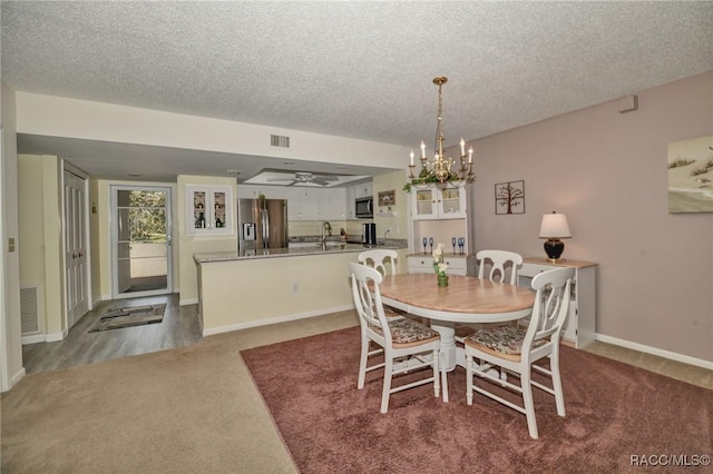 dining space with carpet floors, visible vents, a notable chandelier, and a textured ceiling