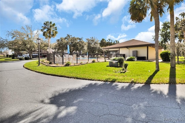 view of property's community with a yard, a swimming pool, and fence