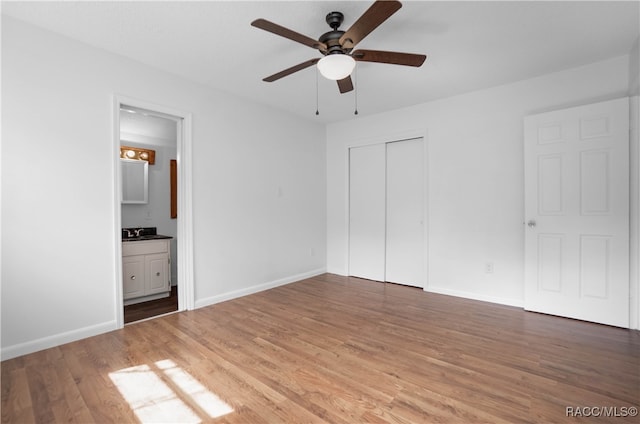 unfurnished bedroom featuring hardwood / wood-style floors, ensuite bathroom, ceiling fan, and a closet