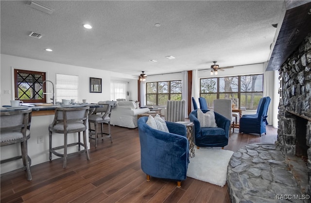 living room featuring ceiling fan, dark wood-type flooring, and a textured ceiling