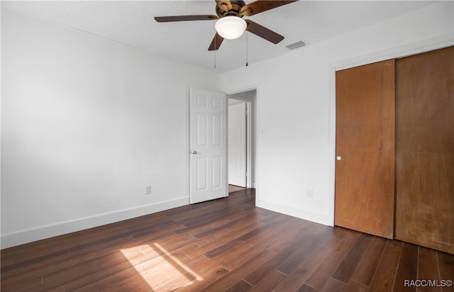 unfurnished bedroom with dark hardwood / wood-style flooring, a closet, and ceiling fan