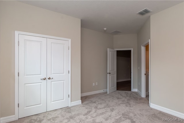 unfurnished bedroom featuring light carpet and a closet