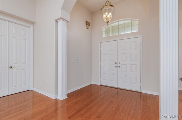 entryway with arched walkways, ornate columns, wood finished floors, and baseboards