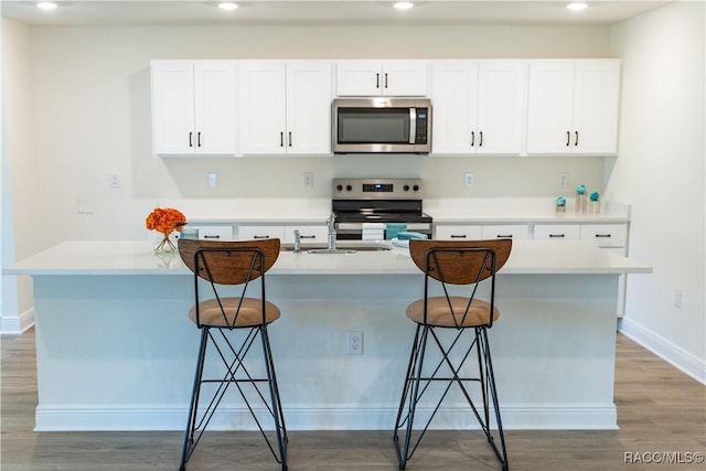 kitchen with a breakfast bar, white cabinetry, and appliances with stainless steel finishes