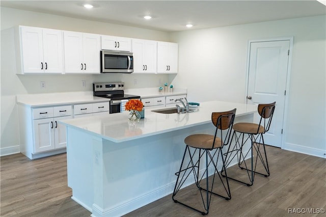 kitchen with a breakfast bar, sink, an island with sink, white cabinetry, and stainless steel appliances