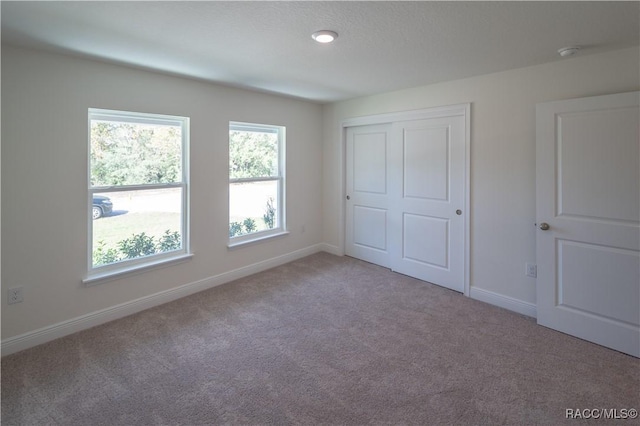 unfurnished bedroom with light carpet and a closet