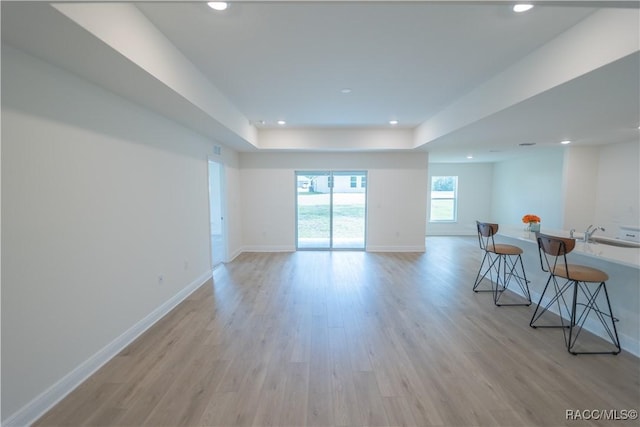 interior space featuring a raised ceiling, light wood-type flooring, and sink