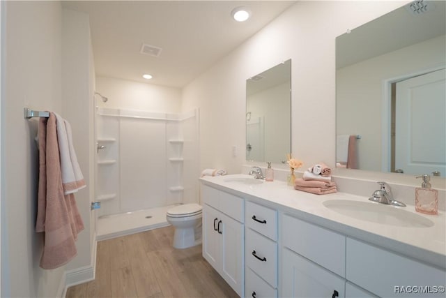 bathroom with a shower, wood-type flooring, vanity, and toilet