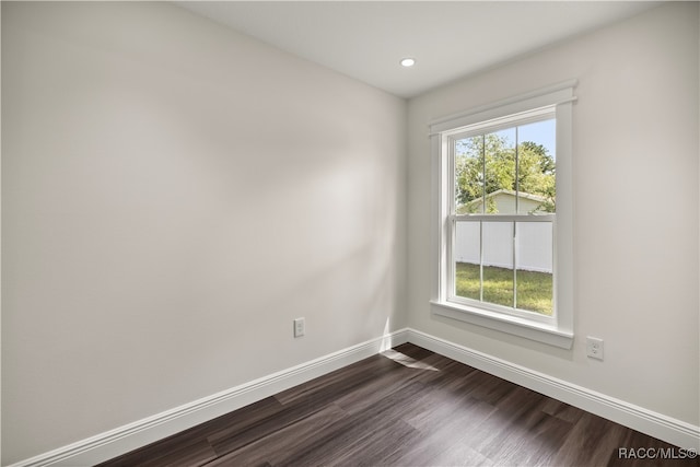 spare room featuring a wealth of natural light, recessed lighting, dark wood-type flooring, and baseboards