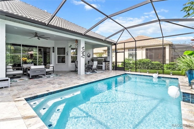 view of pool featuring a lanai, ceiling fan, a patio area, and an outdoor kitchen